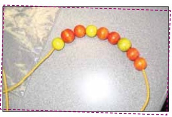 A sequence of wooden beads makes a necklace. From left to right: one yellow sphere and 2 sphere orange, repeated 3 times. 