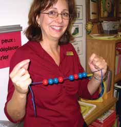  A women holds a necklace that make up a sequence repeated 3 times. The spacing between 2 beads show that a bead is missing. A sequence of spheres. 