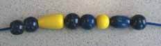 Examples of students correcting the attributes to make the correct sequence. The necklace show attributes of beads colored blue, blue, yellow, blue, blue, yellow, blue, blue. The student finds that the sequence is missing a yellow bead at the end.