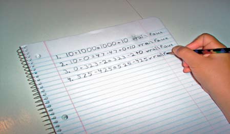 A student is writing mathematical equations in a notebook.