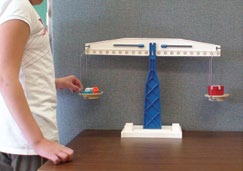 Un élève mesure la masse de deux objets avec une balance à plateaux.