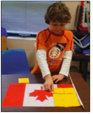 Un élève est en train de recouvrir le drapeau du Canada avec des papillons adhésifs.