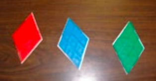 Trois losanges faits de mosaïques géométriques losangent. Le premier est rouge, le second est bleu, le troisième est vert.