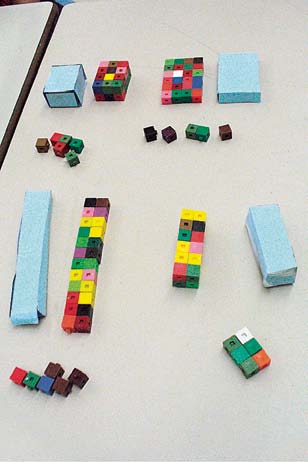 Des prismes construits avec des cubes emboitables, et d’autres en papiers. Ils sont organisés par paires semblables.