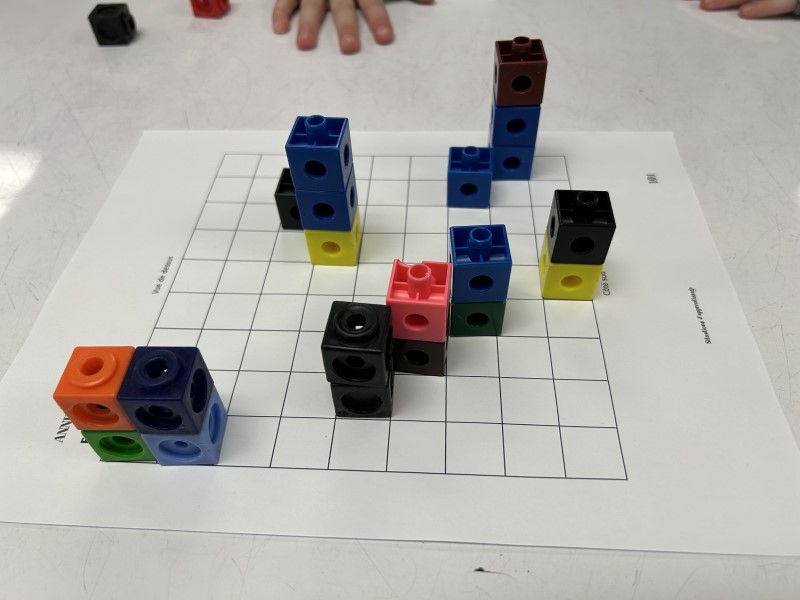 Interlocking blocks are placed on a gridded sheet.