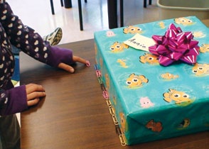 A child measures the length of a gift using paper clips as a unit of measurement.