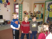 A classroom situation.  There are three students standing in a hoop. There are other students in the classroom.