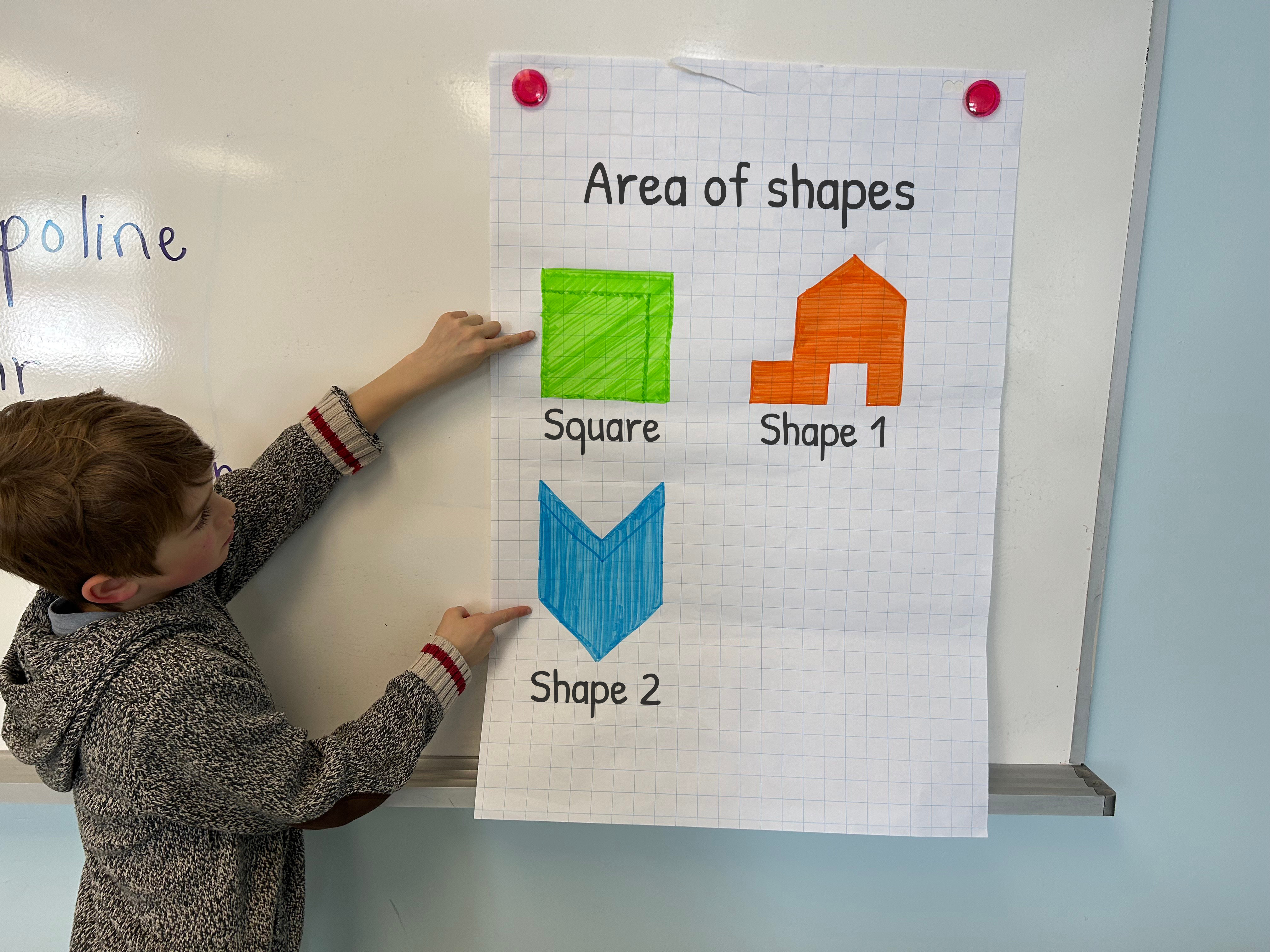 A student is at the board. He shows a poster with the title "Areas of Figures". There is a square, figure one looks like a house, figure two looks like the point of an arrow.