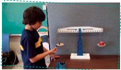 A boy measures two objects on a two-pan scale.