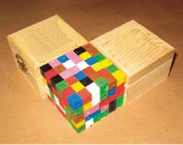 Two boxes in the shape of a right prism, and a right prism built with interlocking cubes. All 3 are of similar volume.