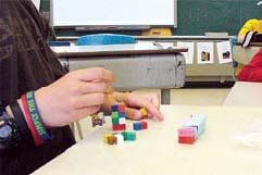 A student works with paper prisms and interlocking cube prisms.